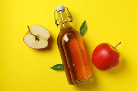 Homemade apple vinegar and ingredients on yellow background-Benefits of Apple Cider Vinegar