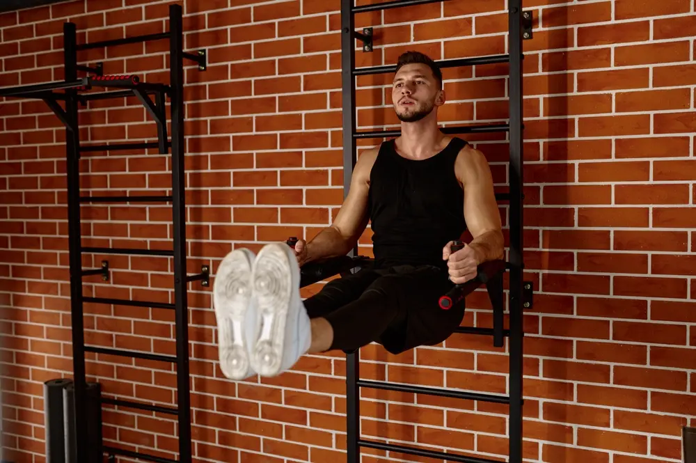 Handsome muscular man doing sport exercises - captain chair excercise