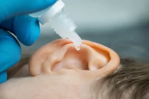 doctor dripping ear drops into patient ear - earache remedies